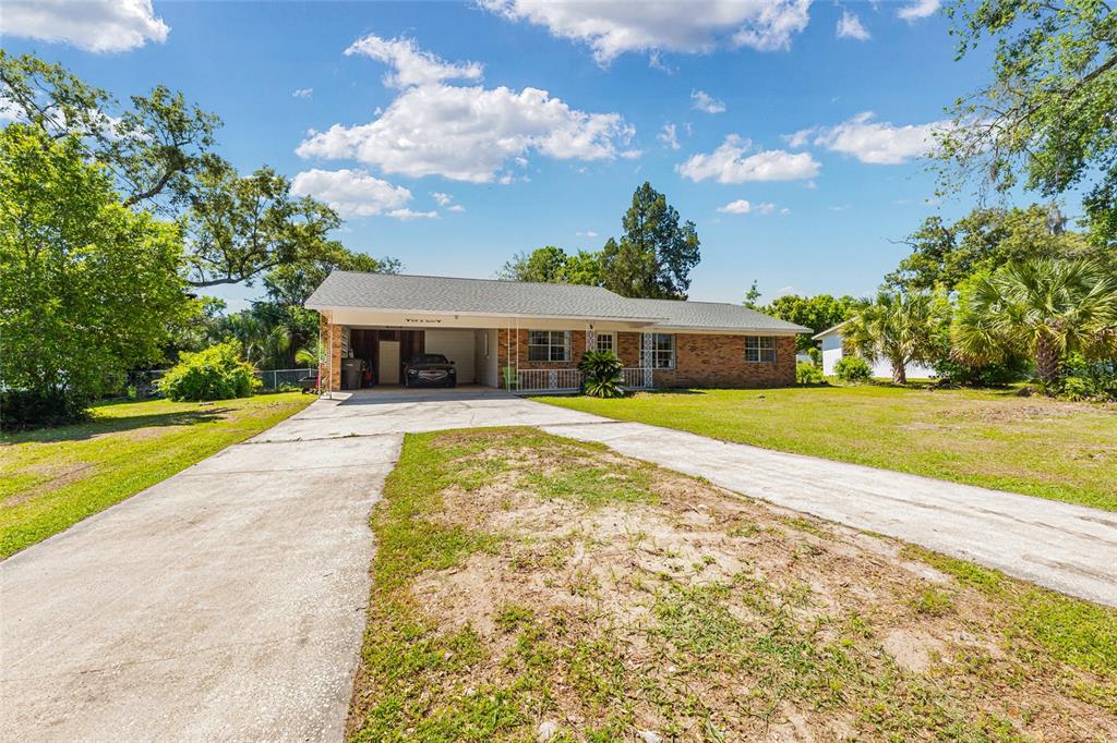 A single-story brick house with a carport and a concrete driveway under a blue sky — 3200 NE 10TH STREET, OCALA, FL