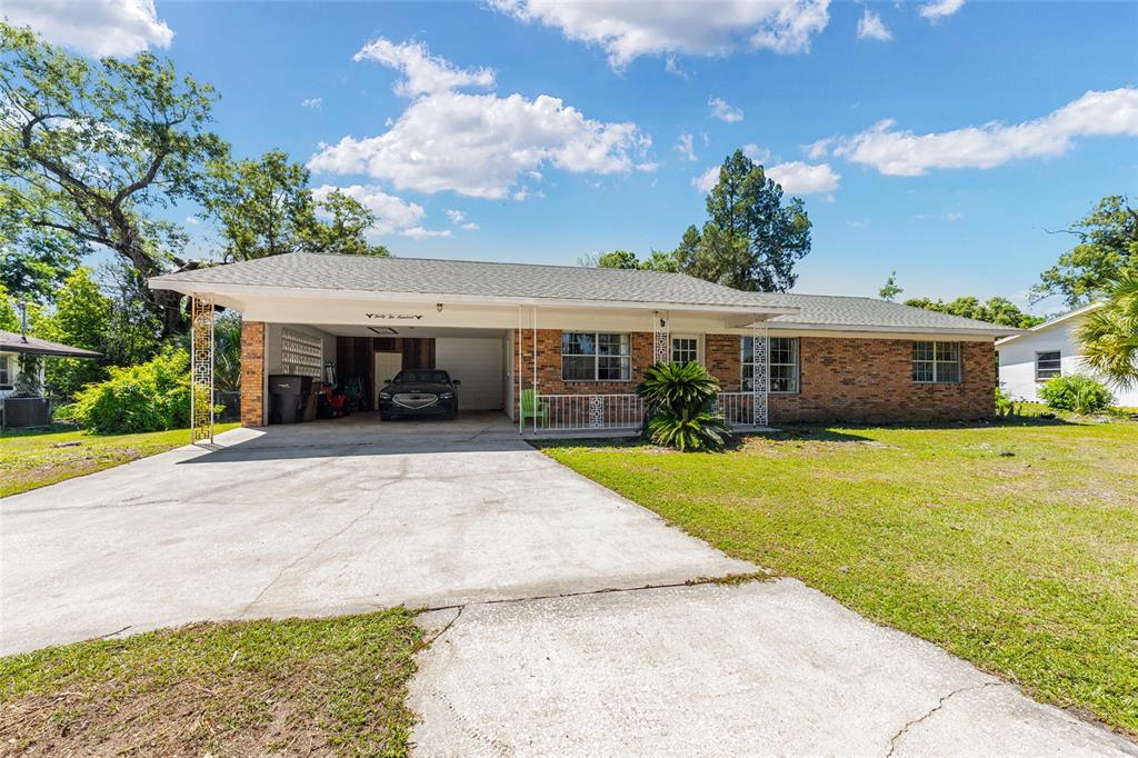 A single-story brick house features a large attached carport and a concrete driveway — 3200 NE 10TH STREET, OCALA, FL