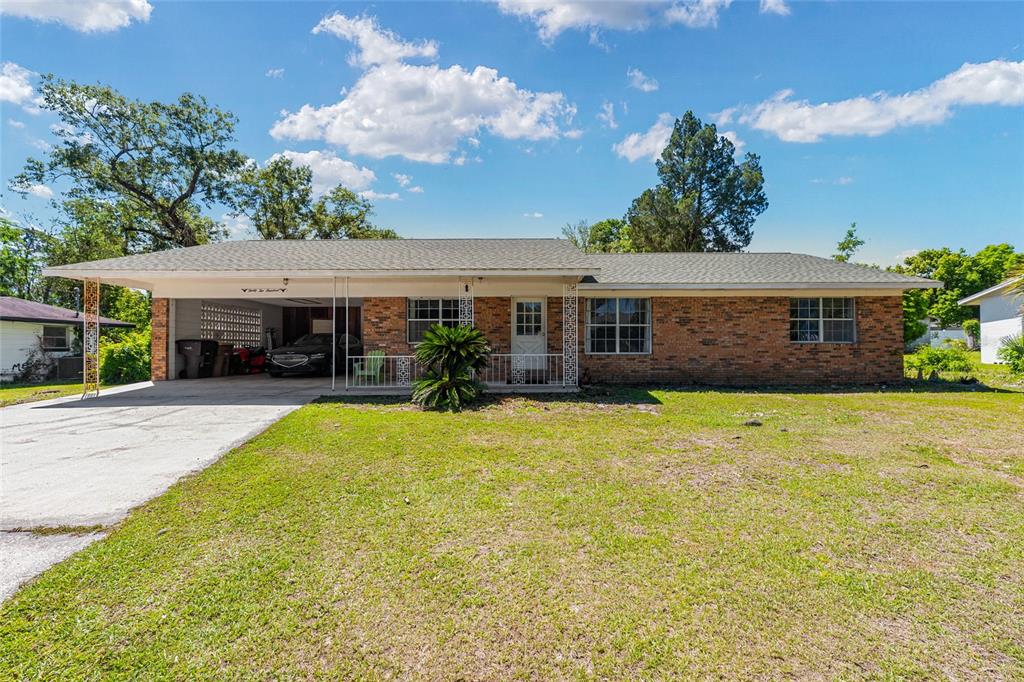 A single-story brick house features a large attached carport and a front lawn — 3200 NE 10TH STREET, OCALA, FL