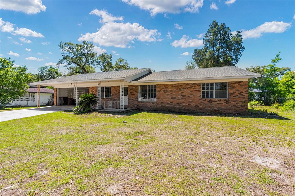 A single-story brick house features a carport, a front porch, and a grassy yard — 3200 NE 10TH STREET, OCALA, FL