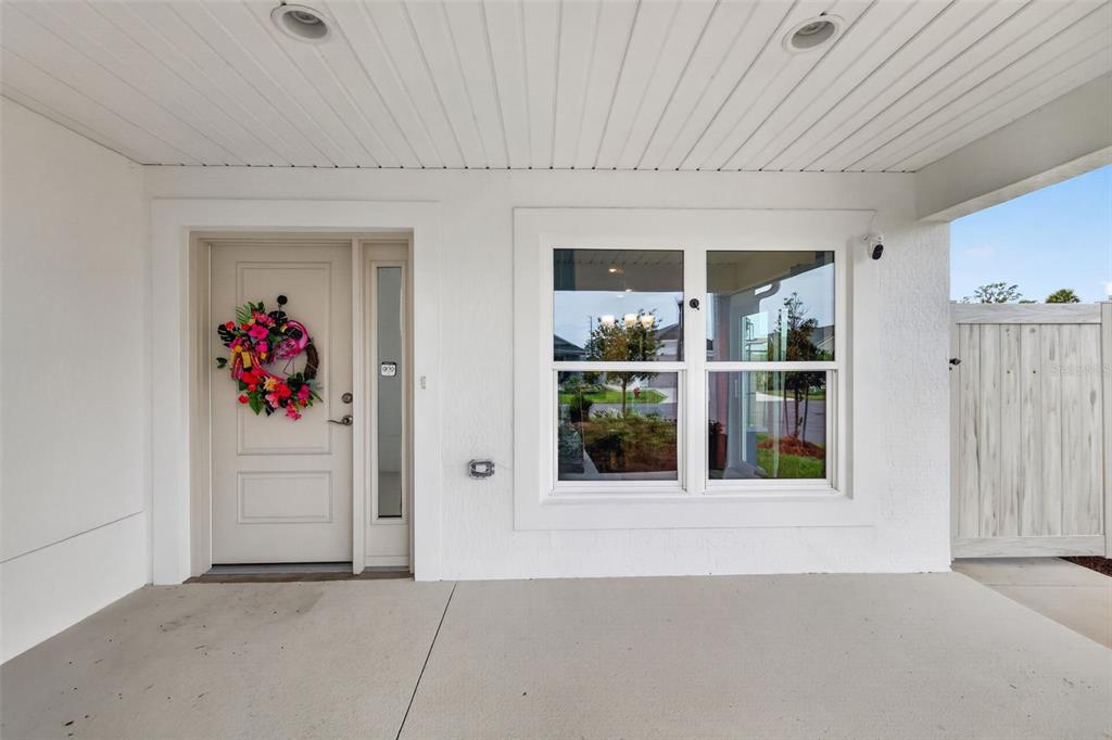 A covered entryway features a white front door with a floral wreath and a window — 1674 CADORETTE DRIVE, THE VILLAGES, FL