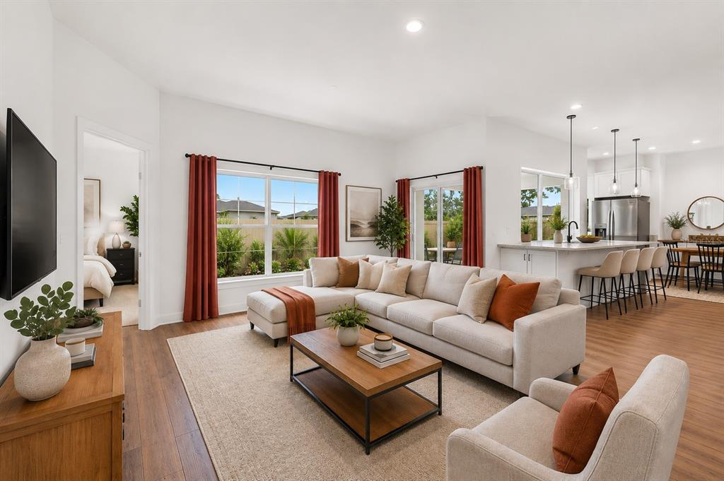 A living room with a sectional sofa, coffee table, and an open kitchen in the background — 1674 CADORETTE DRIVE, THE VILLAGES, FL