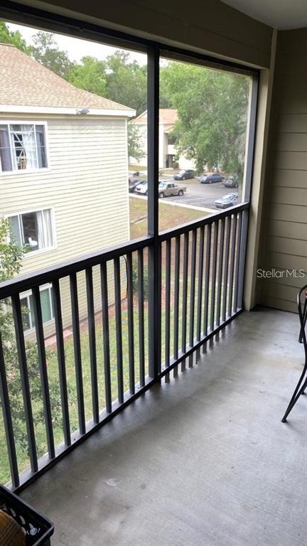 A screened-in balcony overlooks a parking lot and a neighboring apartment building — 3800 SW 20TH AVENUE AVENUE UNIT 209, GAINESVILLE, FL
