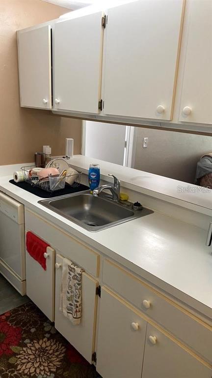 A kitchen features white cabinets, a stainless steel sink, and a dishwasher under white countertops — 3800 SW 20TH AVENUE AVENUE UNIT 209, GAINESVILLE, FL