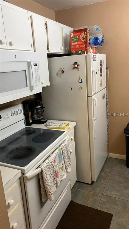 A kitchen features white cabinets, a white electric stove, a microwave, and a white refrigerator — 3800 SW 20TH AVENUE AVENUE UNIT 209, GAINESVILLE, FL