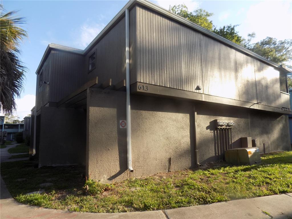 A two-story building exterior features vertical wood siding, a stucco lower level, and a downspout — 613 SW 75 STREET UNIT 101, GAINESVILLE, FL