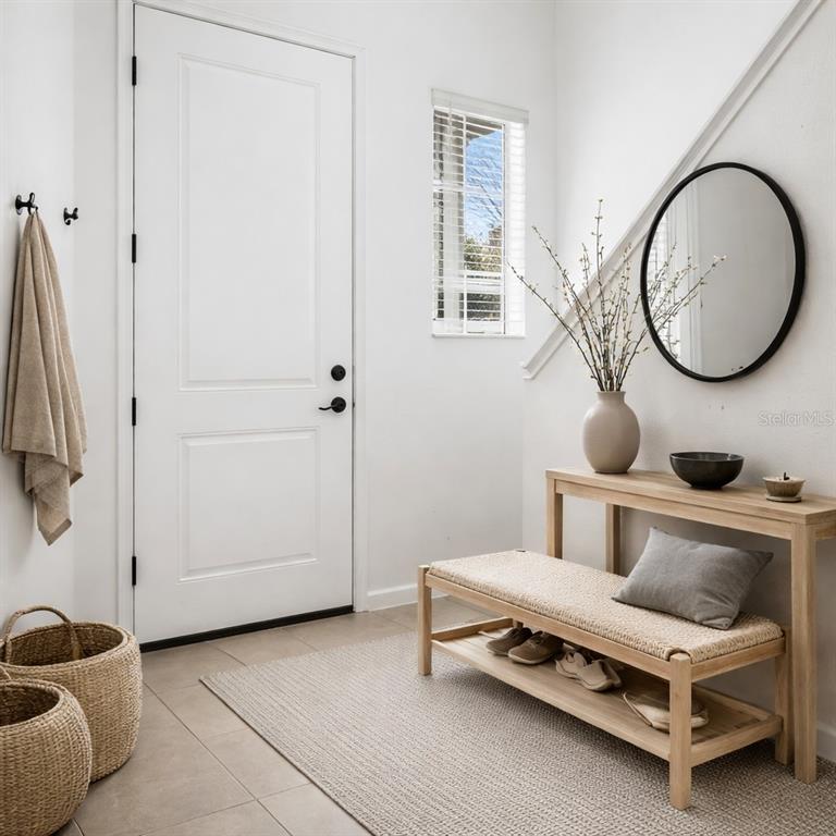 A bright entryway features a white door, a wooden bench, a console table, and baskets — 213 TRINITY RIDGE CIRCLE, DAVENPORT, FL