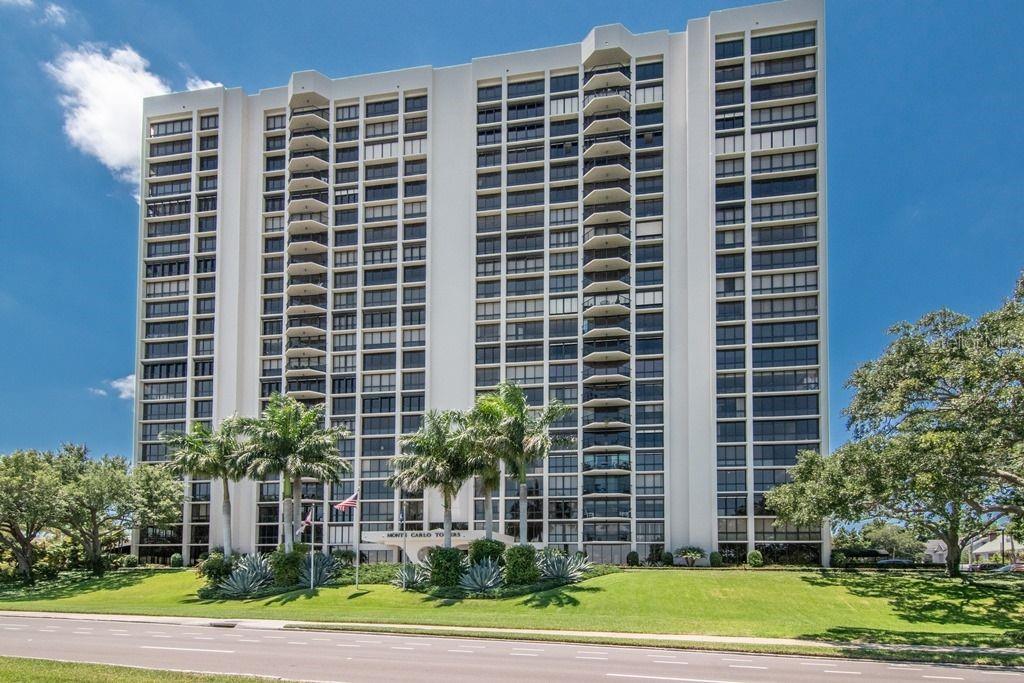 A tall, white residential high-rise building stands behind a manicured lawn and palm trees — 3301 BAYSHORE BOULEVARD UNIT 302E, TAMPA, FL