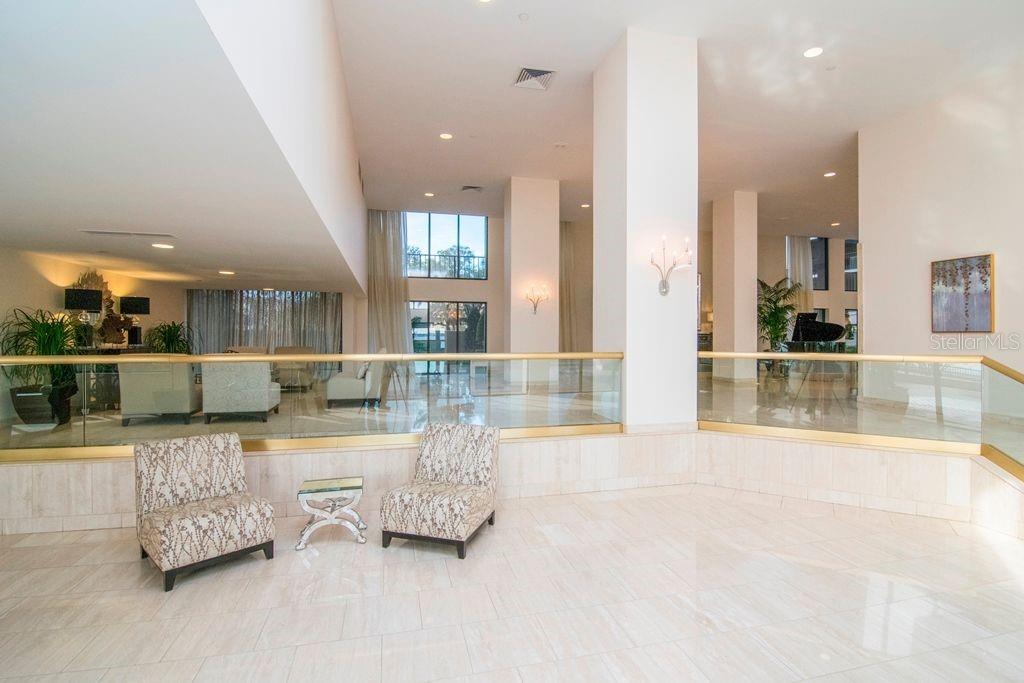 A spacious lobby features marble floors, a glass railing, and two patterned armchairs — 3301 BAYSHORE BOULEVARD UNIT 302E, TAMPA, FL