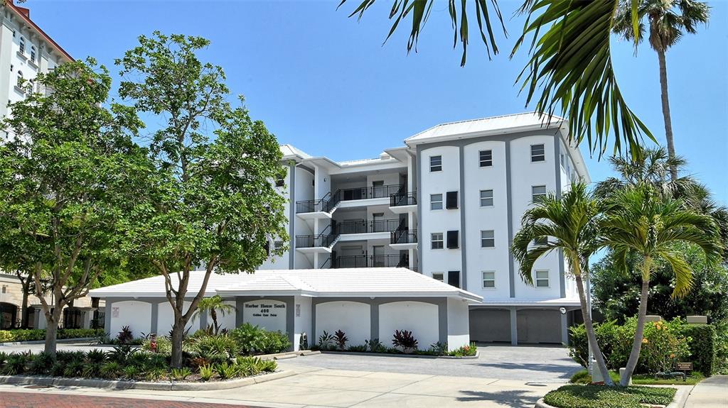 A multi-story white apartment building with a covered ground-level parking area and palm trees — 400 GOLDEN GATE POINT UNIT 31, SARASOTA, FL