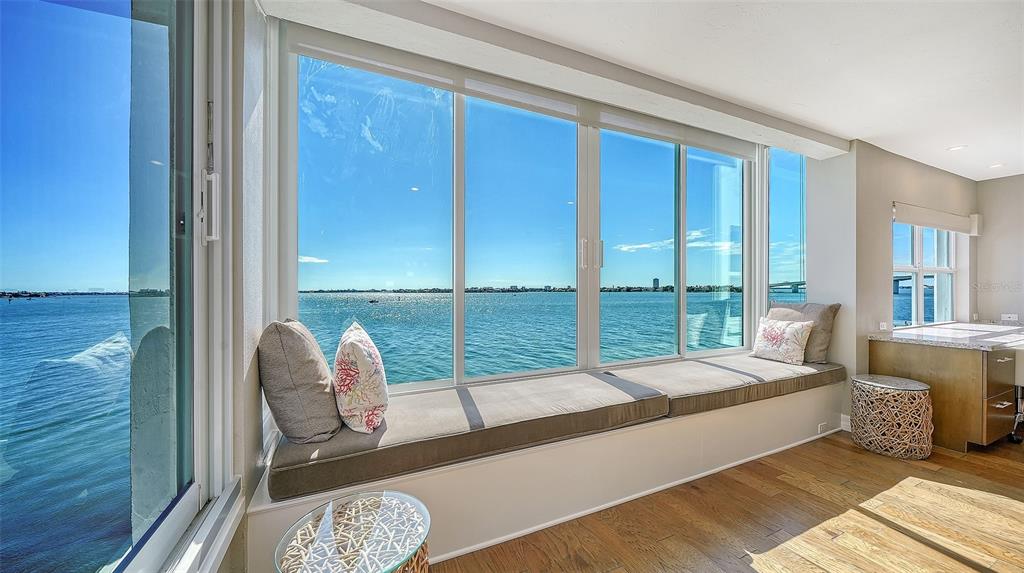 A window seat with cushions overlooks a body of water in a bright room — 400 GOLDEN GATE POINT UNIT 31, SARASOTA, FL