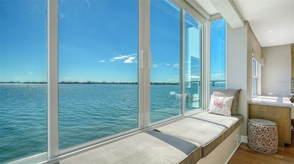 A window seat with gray cushions overlooks a large body of water and a bridge — 400 GOLDEN GATE POINT UNIT 31, SARASOTA, FL