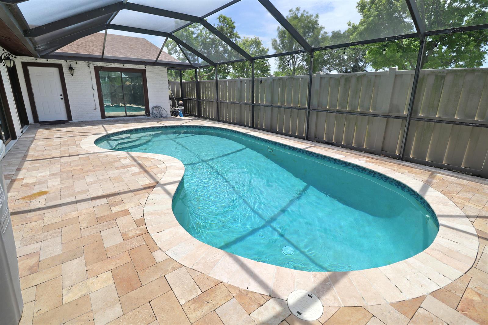 A kidney-shaped swimming pool with a paver deck is enclosed by a screened lanai — 9713 Boca Gardens Parkway # D, Boca Raton FL 33496, BOCA RATON, FL