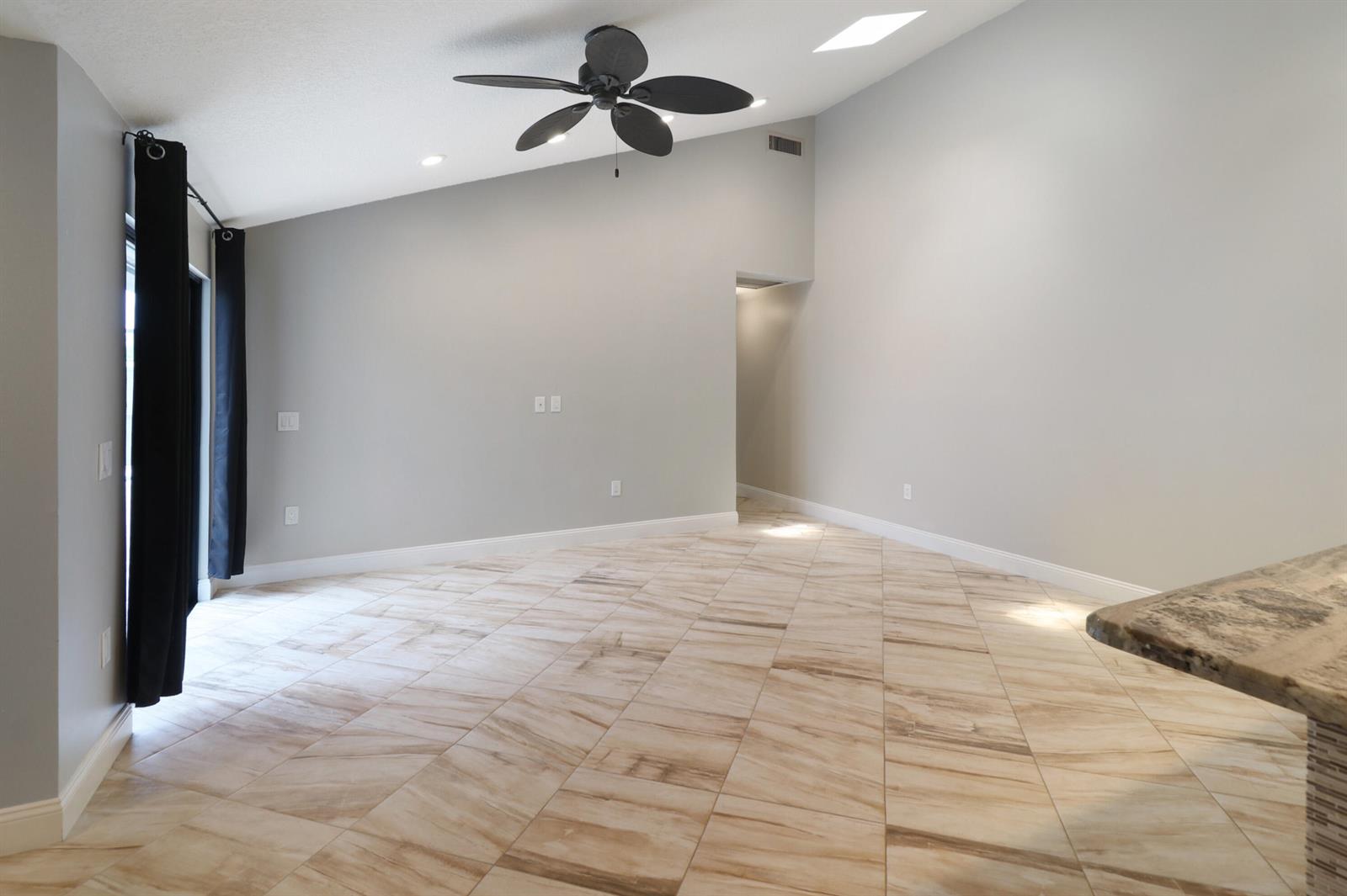 A spacious room with vaulted ceilings, a ceiling fan, and light-colored tile flooring — 9713 Boca Gardens Parkway # D, Boca Raton FL 33496, BOCA RATON, FL