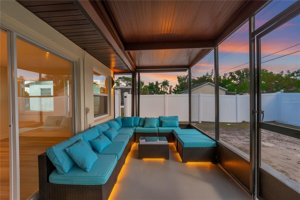 A covered patio features a large sectional sofa with teal cushions and under-seat lighting — 1461 ROYAL ROAD, VENICE, FL