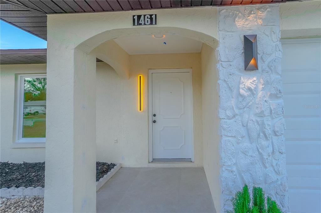 The exterior entrance features a white door, stone siding, and a house number above — 1461 ROYAL ROAD, VENICE, FL