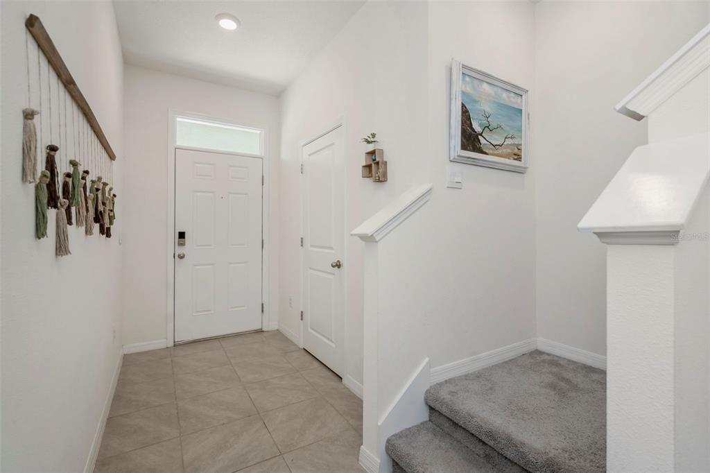 A bright entryway features tile flooring, a white front door, and carpeted stairs — 17226 AMBER ASPEN WAY, LAND O LAKES, FL