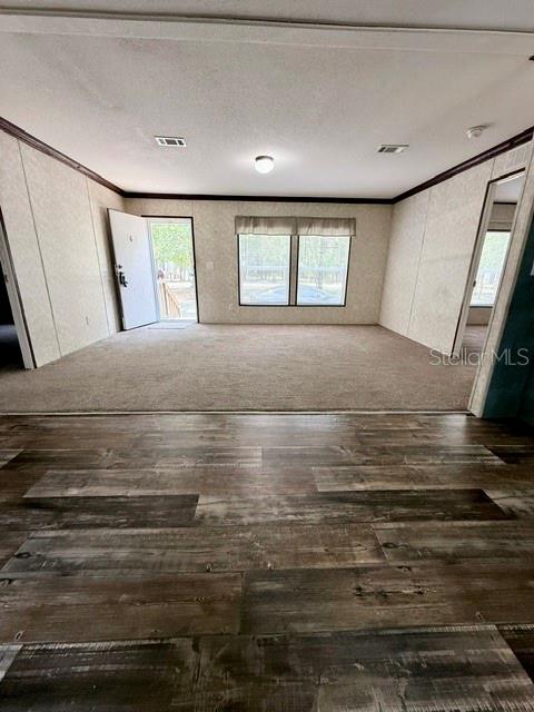 A room with wood-look flooring transitions to a carpeted living area with a front door — 877 SE 38 WAY, MELROSE, FL