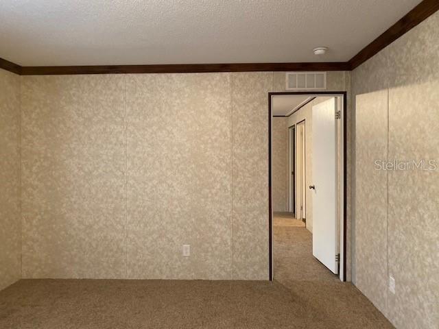 An interior view shows a carpeted room with patterned wallpaper and a doorway leading elsewhere — 877 SE 38 WAY, MELROSE, FL