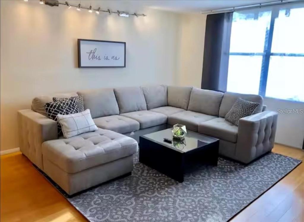 A living room features a large gray sectional sofa, a glass-top coffee table, and area rug — 701 S MADISON AVENUE UNIT 422, CLEARWATER, FL