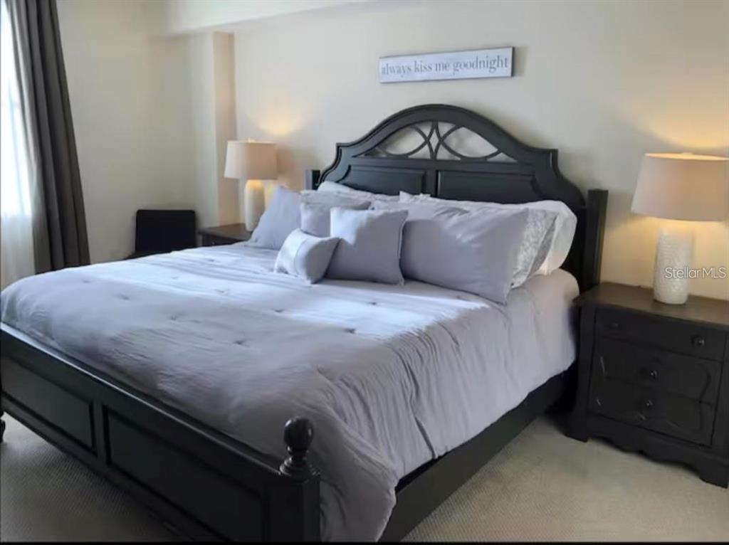 A bedroom features a dark wood bed frame, light gray bedding, and matching nightstands with lamps — 701 S MADISON AVENUE UNIT 422, CLEARWATER, FL