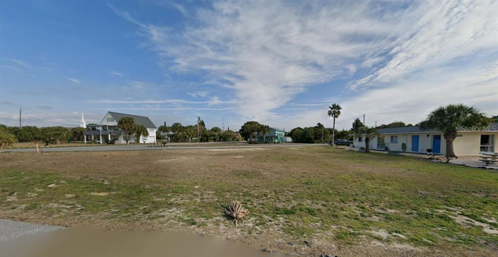 A vacant, grassy lot sits in front of a residential street with several houses — 601 GRANADA CIRCLE, PANAMA CITY BEACH, FL