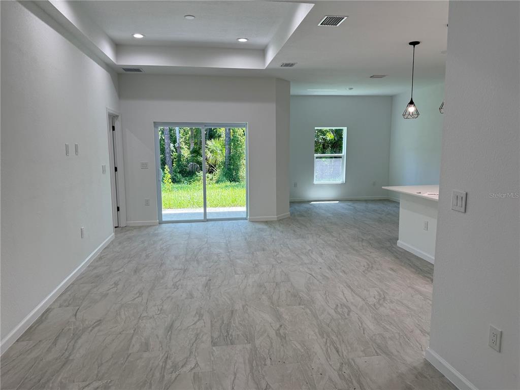 An open-concept living area features light gray tile flooring, a tray ceiling, and sliding glass doors — 1392 ALABELLE LANE, NORTH PORT, FL