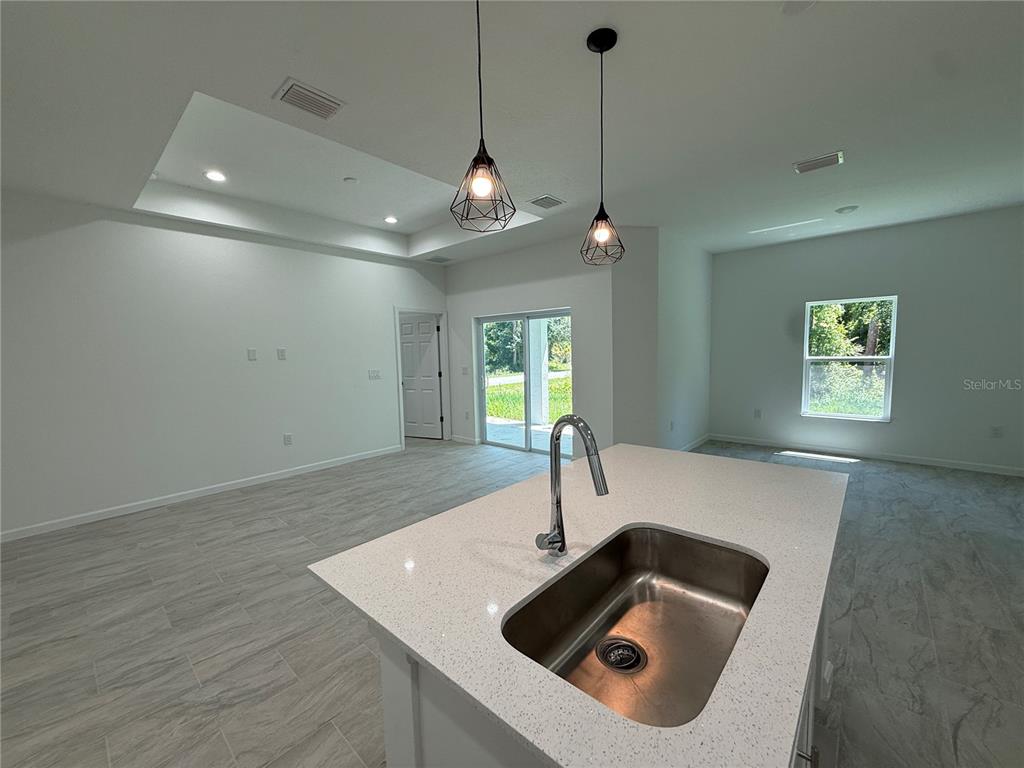 A kitchen island with a stainless steel sink sits in an open-concept living area — 1392 ALABELLE LANE, NORTH PORT, FL