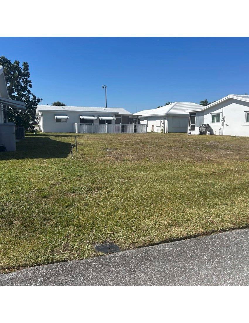 A vacant, grassy residential lot sits between two single-story houses under a clear blue sky — 2931 NW 1st Drive, Pompano Beach FL 33064, POMPANO BEACH, FL