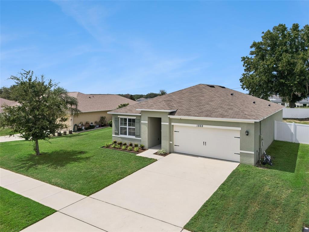 A single-story house with a two-car garage, a concrete driveway, and a green lawn — 1869 SUNSET RIDGE DRIVE, MASCOTTE, FL