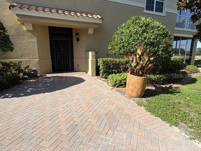A paved walkway leads to the front entrance of a tan stucco building — 1425 EMERALD DUNES DRIVE UNIT 17, SUN CITY CENTER, FL