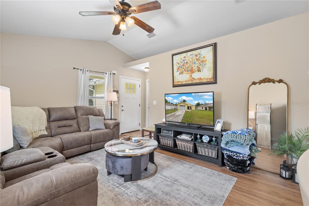 A living room features a brown sectional sofa, a round coffee table, and a television — 308 SW 2ND AVENUE, CHIEFLAND, FL