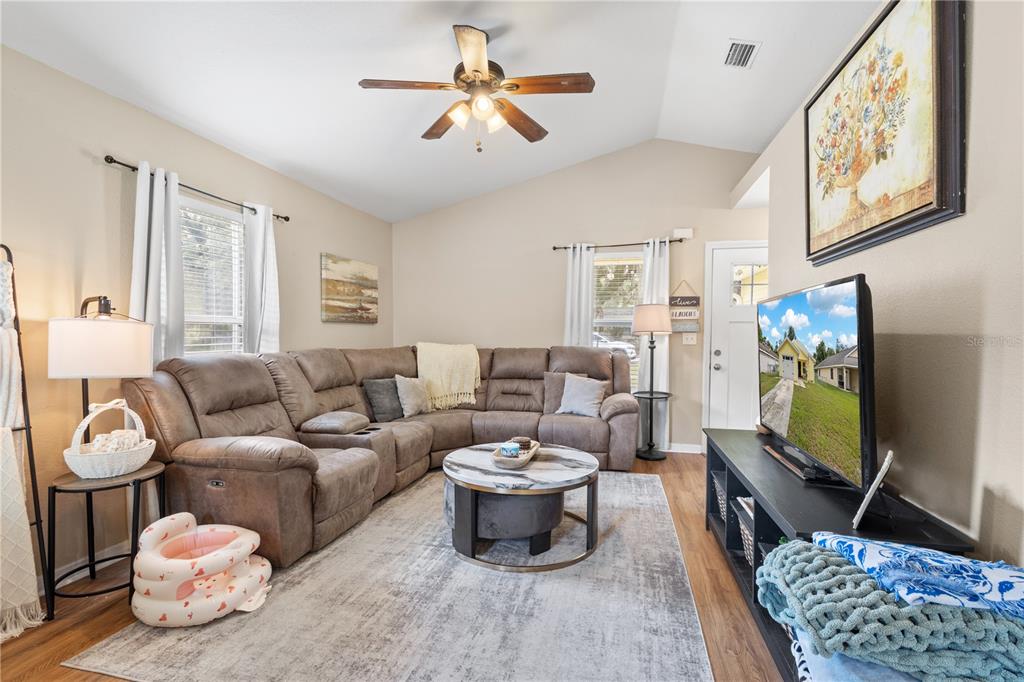 A living room features a brown sectional sofa, a round coffee table, and a television — 308 SW 2ND AVENUE, CHIEFLAND, FL