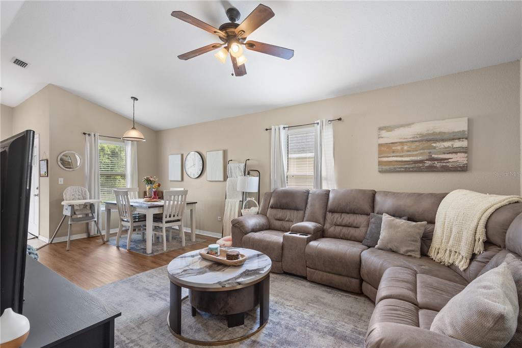 A living room and dining area feature wood-look flooring, a sectional sofa, and a ceiling fan — 308 SW 2ND AVENUE, CHIEFLAND, FL