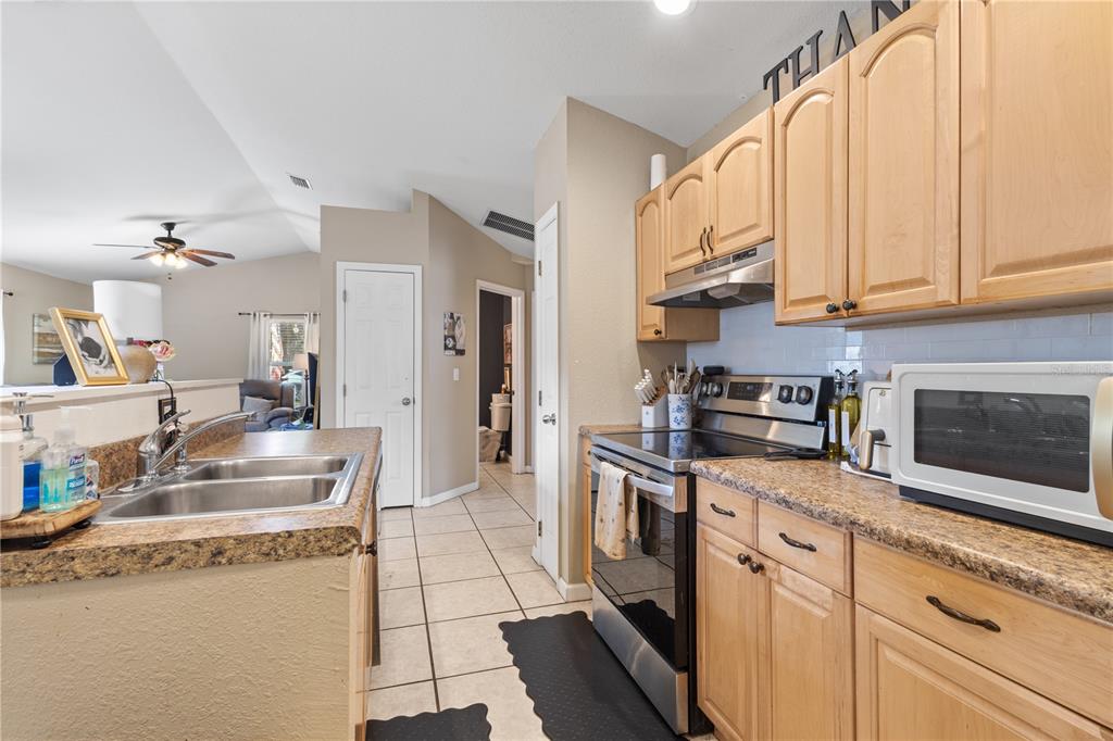 A kitchen features light wood cabinets, laminate countertops, stainless steel appliances, and tile flooring — 308 SW 2ND AVENUE, CHIEFLAND, FL