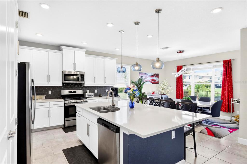 A kitchen features white cabinets, a central island with a sink, and an adjacent dining area — 3073 MOUNTAIN SPRUCE TERRACE, WESLEY CHAPEL, FL