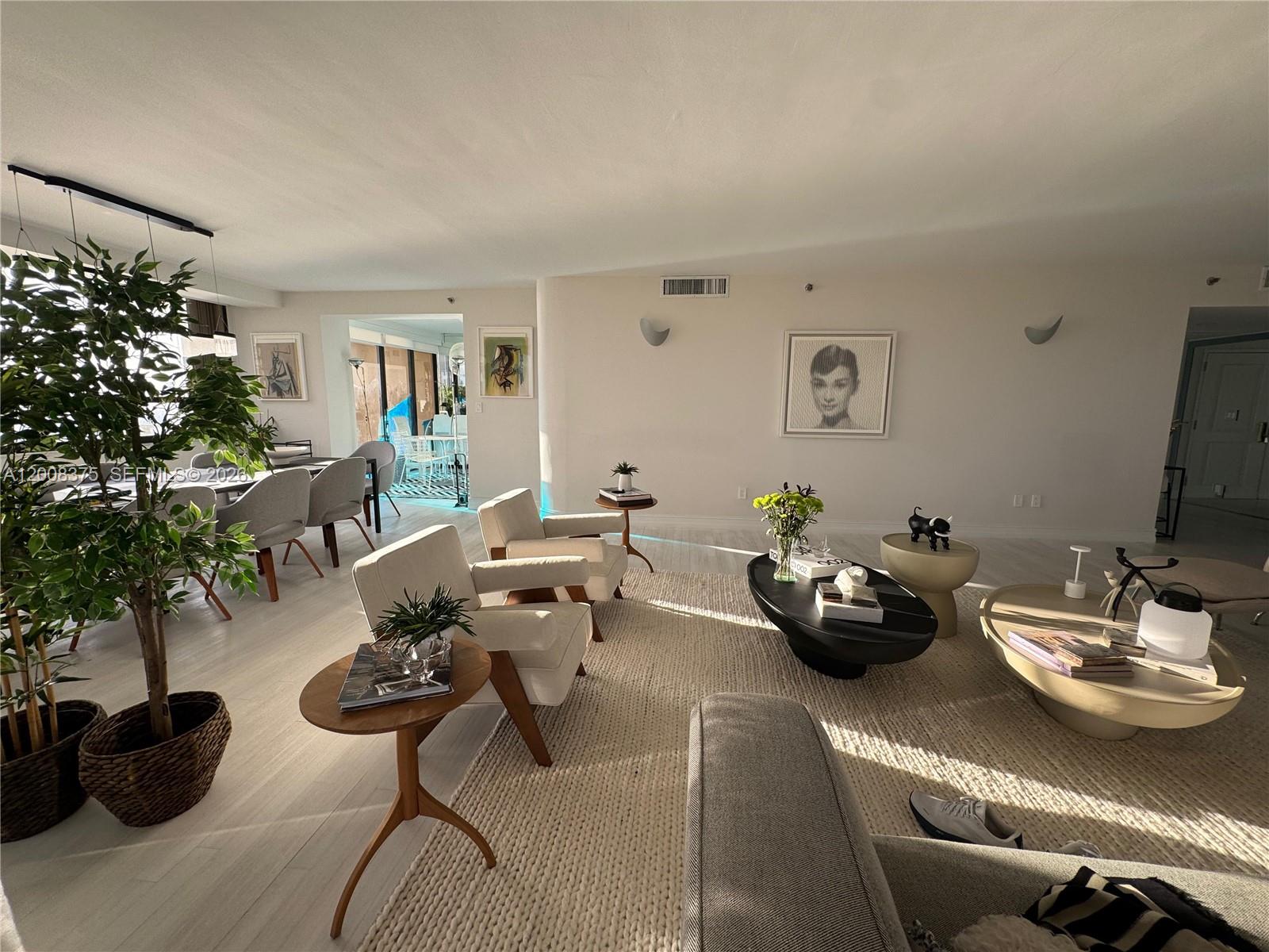 A bright, open-concept living and dining area features light wood flooring and modern neutral furniture — 11113 Biscayne Blvd # 558, Miami FL 33181, MIAMI, FL