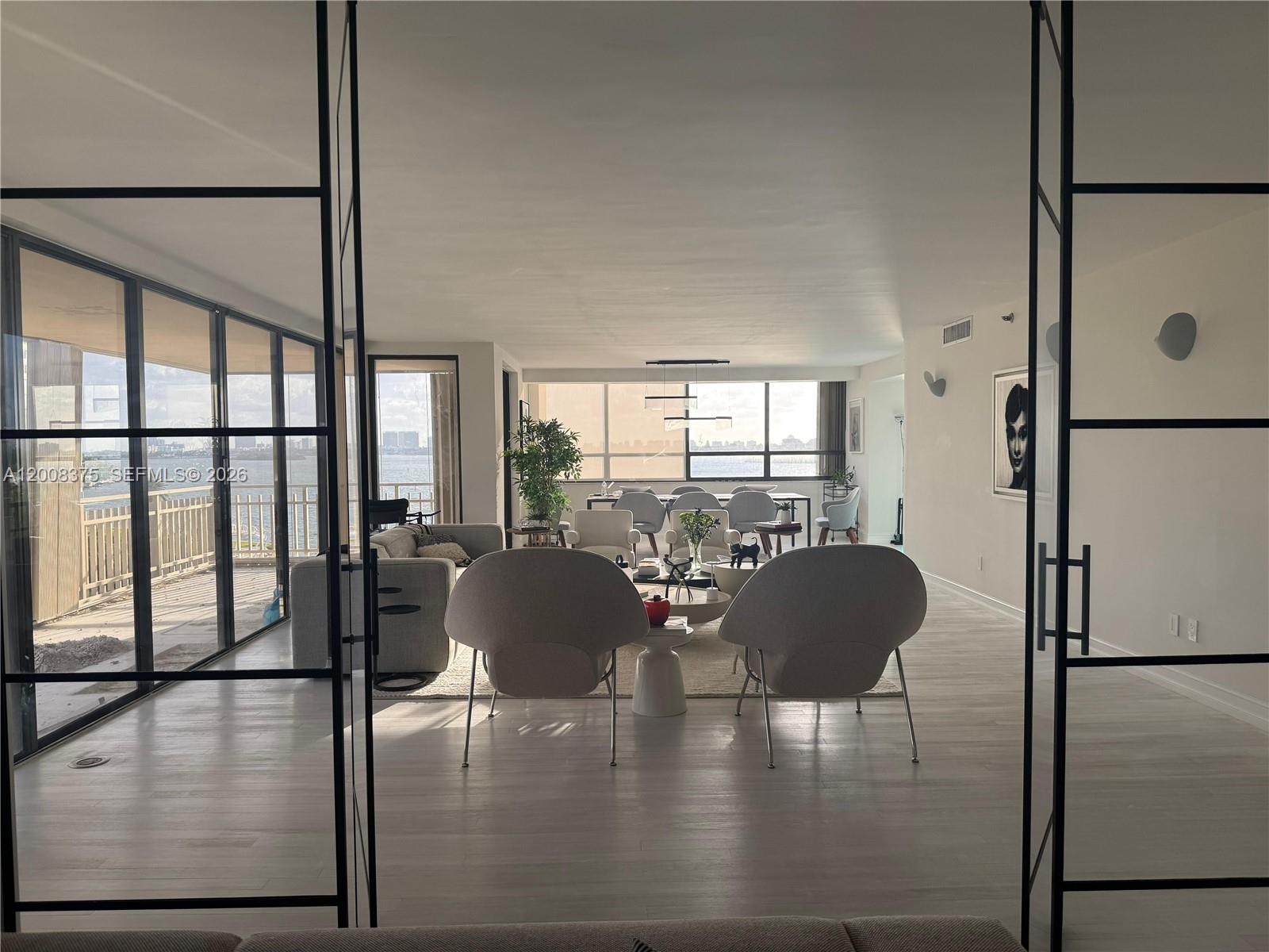 A bright, open-concept living and dining area features floor-to-ceiling windows overlooking the water — 11113 Biscayne Blvd # 558, Miami FL 33181, MIAMI, FL