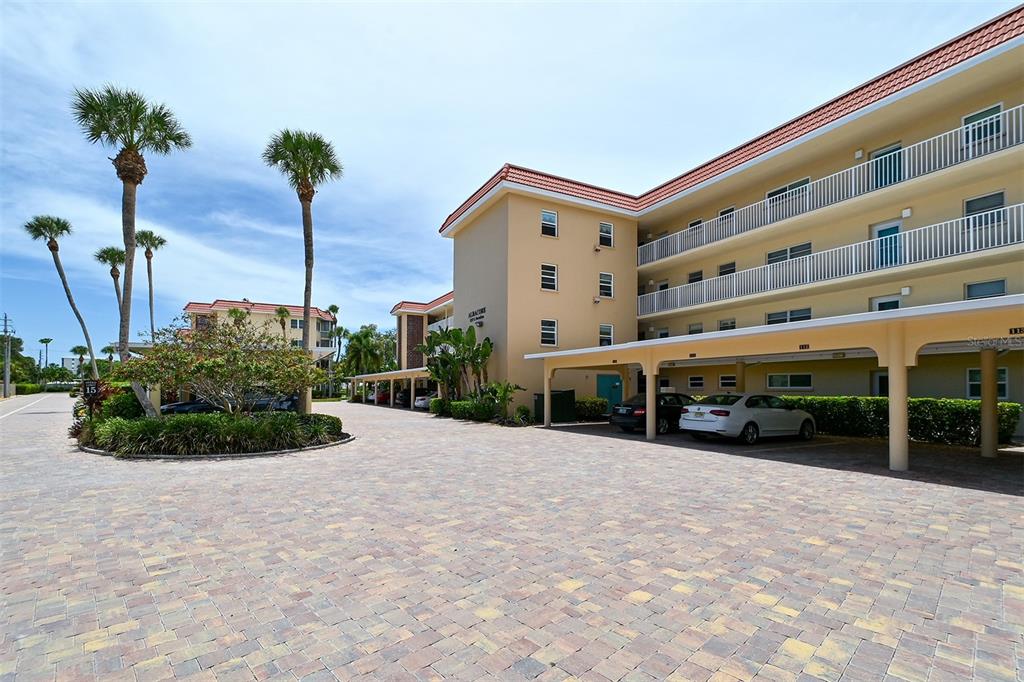 An exterior view of a multi-story apartment building with covered parking and palm trees — 1257 S PORTOFINO DRIVE UNIT 36, SARASOTA, FL