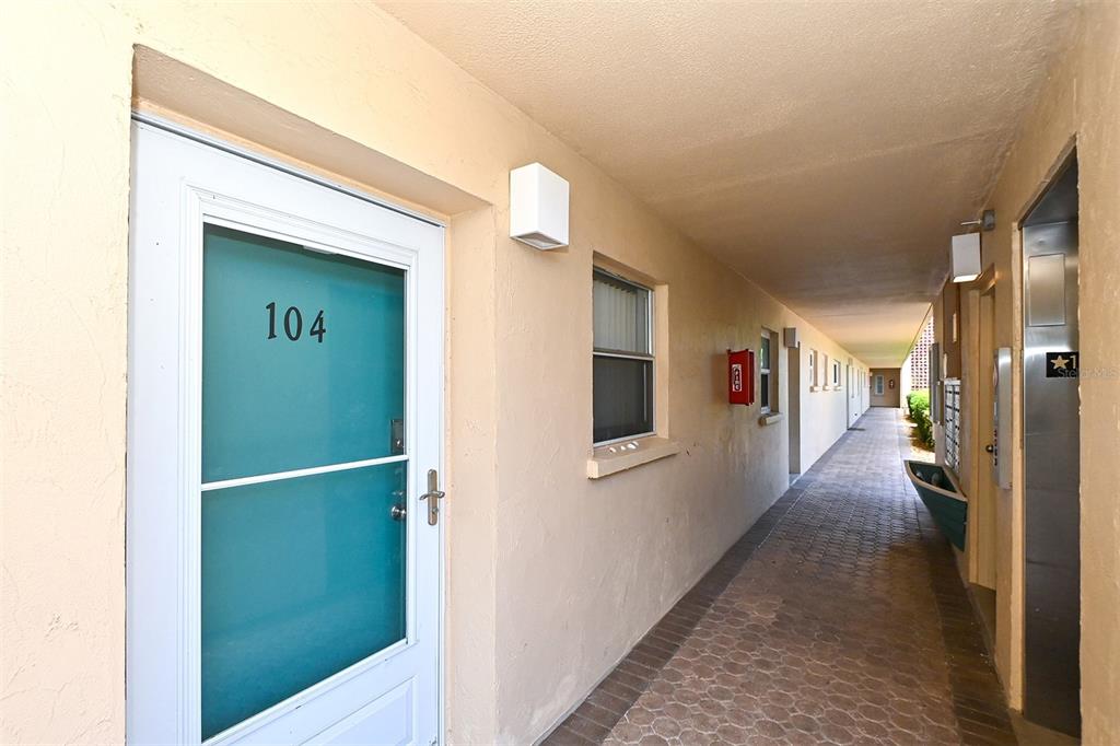 An outdoor apartment building walkway features a door labeled 104 and a paved floor — 1257 S PORTOFINO DRIVE UNIT 36, SARASOTA, FL