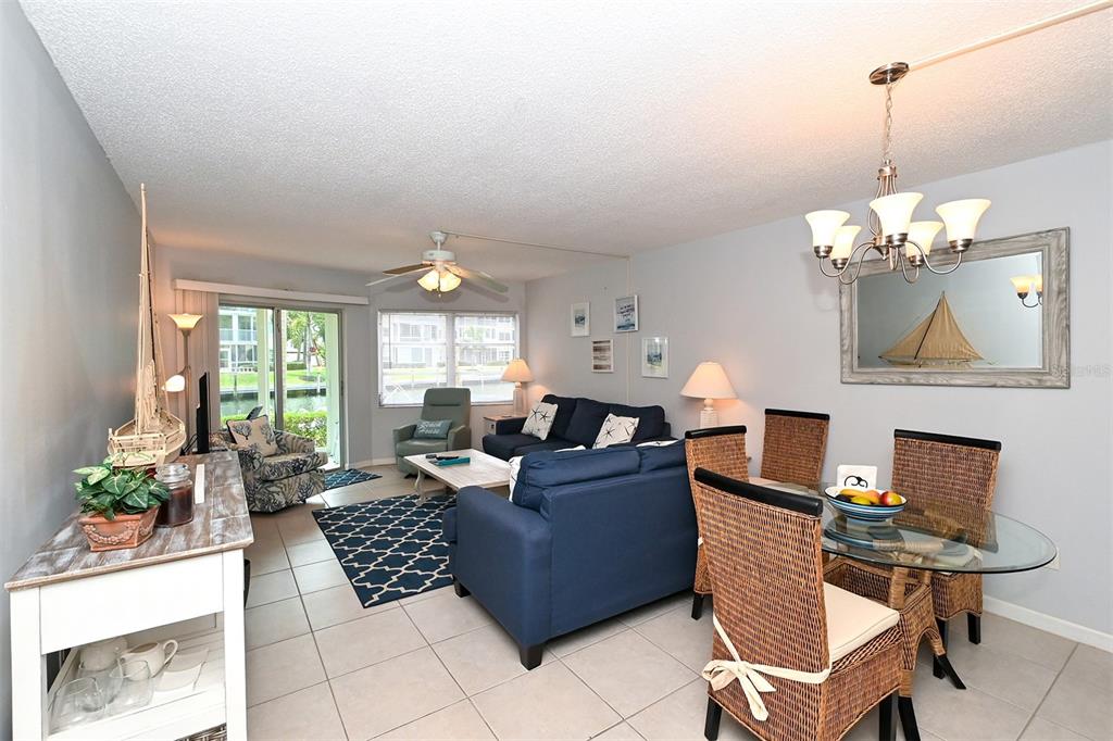 A living and dining area with blue furniture, tile floors, and a view of water — 1257 S PORTOFINO DRIVE UNIT 36, SARASOTA, FL