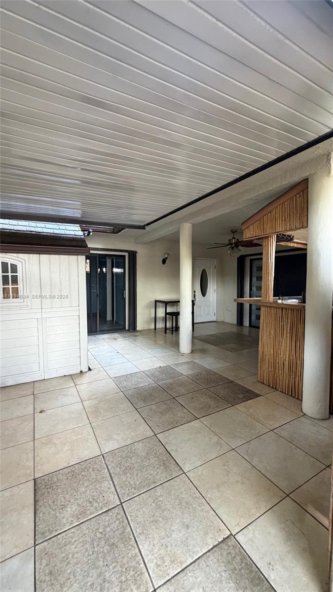 A covered patio features tiled flooring, a tiki bar, and a white storage shed — 2450 W 67th Pl # 12, Hialeah FL 33016, HIALEAH, FL