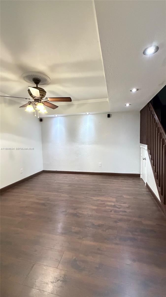 An empty room features dark wood-look flooring, a ceiling fan, and a wooden staircase — 2450 W 67th Pl # 12, Hialeah FL 33016, HIALEAH, FL