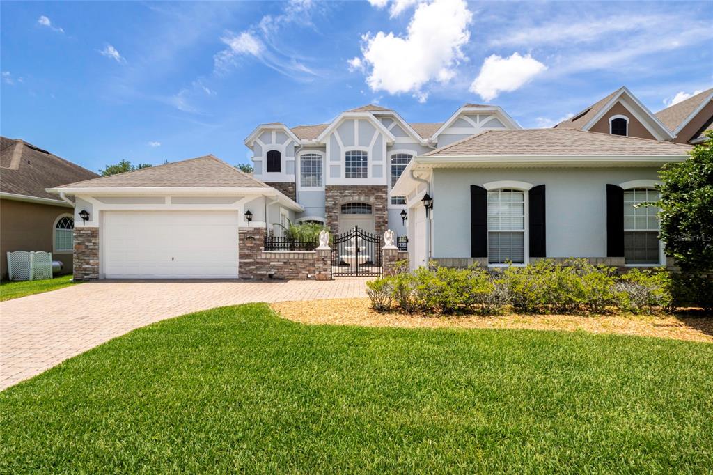 A two-story house with a stone-accented facade, a gated courtyard, and a paved driveway — 16431 BRISTOL LAKE CIRCLE, ORLANDO, FL