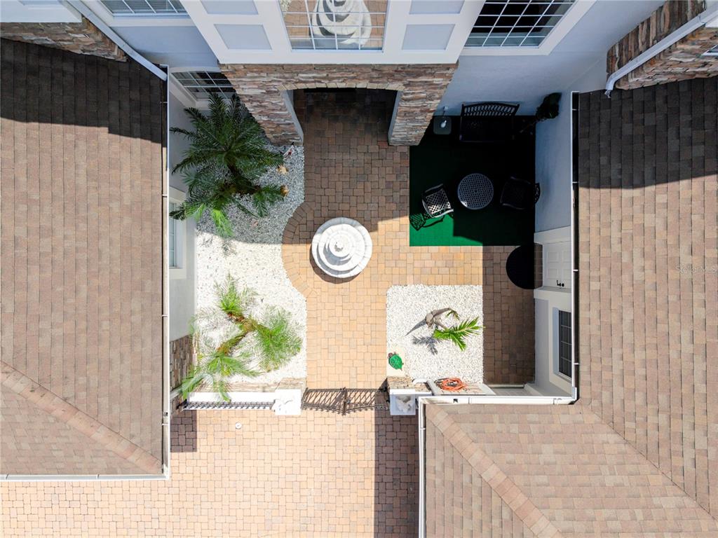 An aerial view of a paved courtyard featuring a central fountain and small palm trees — 16431 BRISTOL LAKE CIRCLE, ORLANDO, FL
