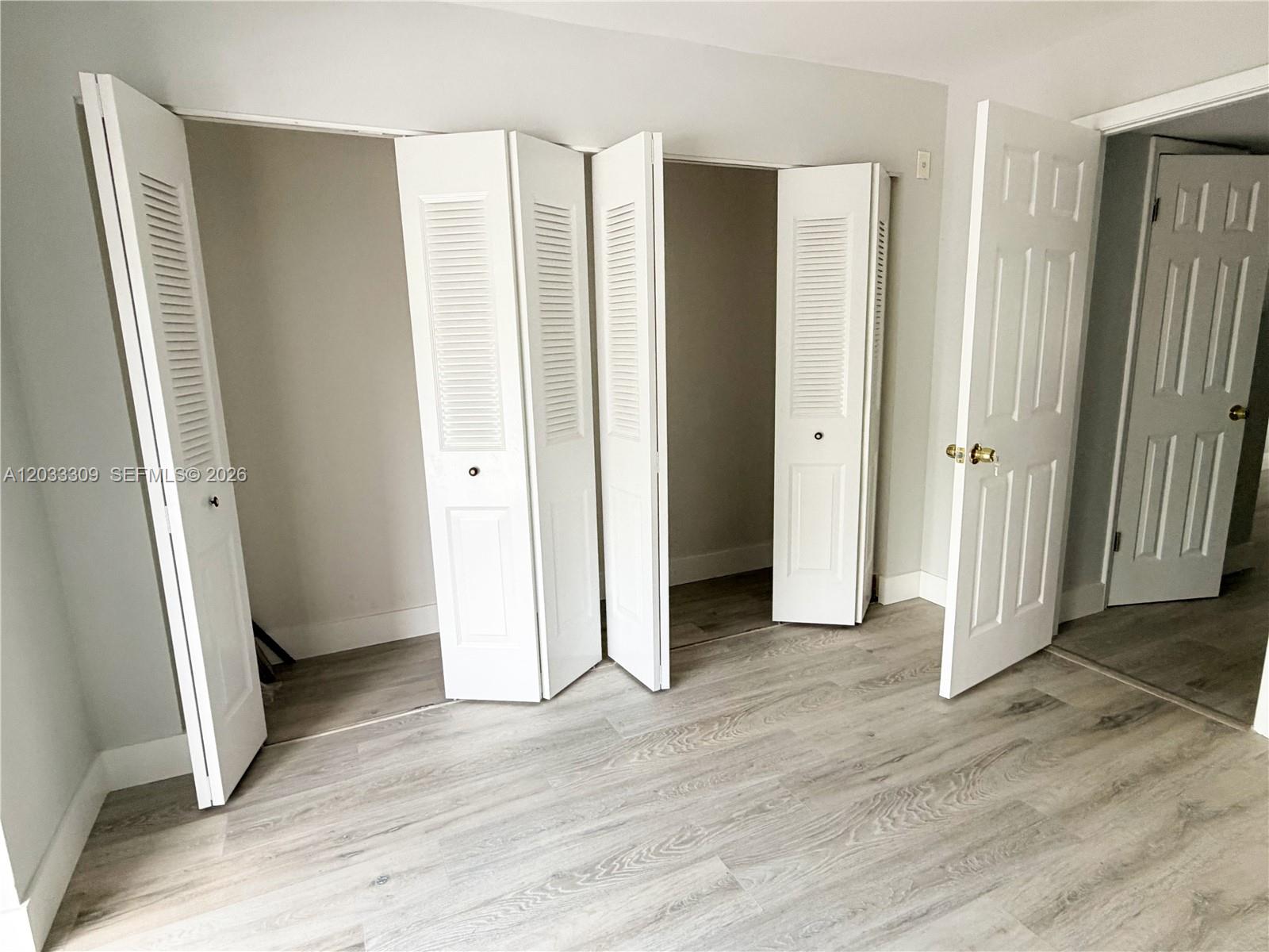 A room features light wood-look flooring, white walls, and open bi-fold closet doors — 178 Durham C # 178, Deerfield Beach FL 33442, DEERFIELD BEACH, FL