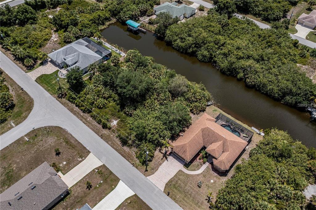 An aerial view shows two houses with pools along a canal surrounded by dense vegetation — 13958 ALLAMANDA CIRCLE, PORT CHARLOTTE, FL