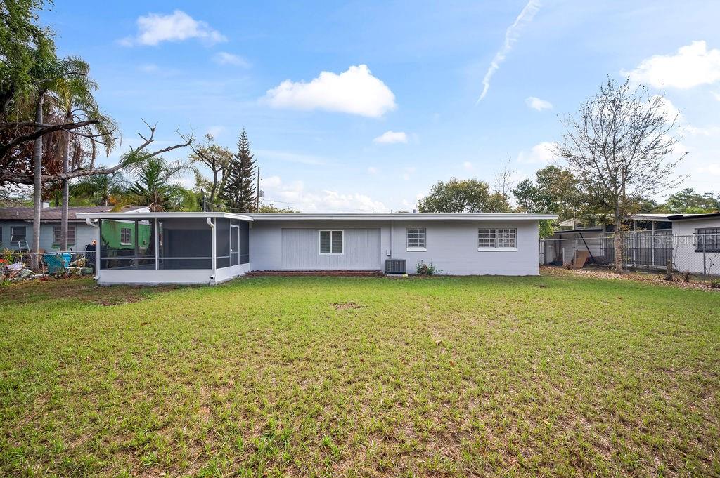 The back exterior of a single-story house with a screened-in porch and a grassy yard — 600 VENTURA AVENUE, ORLANDO, FL