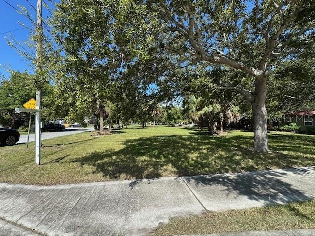 A grassy, tree-filled vacant lot sits next to a sidewalk and a dead-end street sign — 380 HANCOCK STREET, DUNEDIN, FL