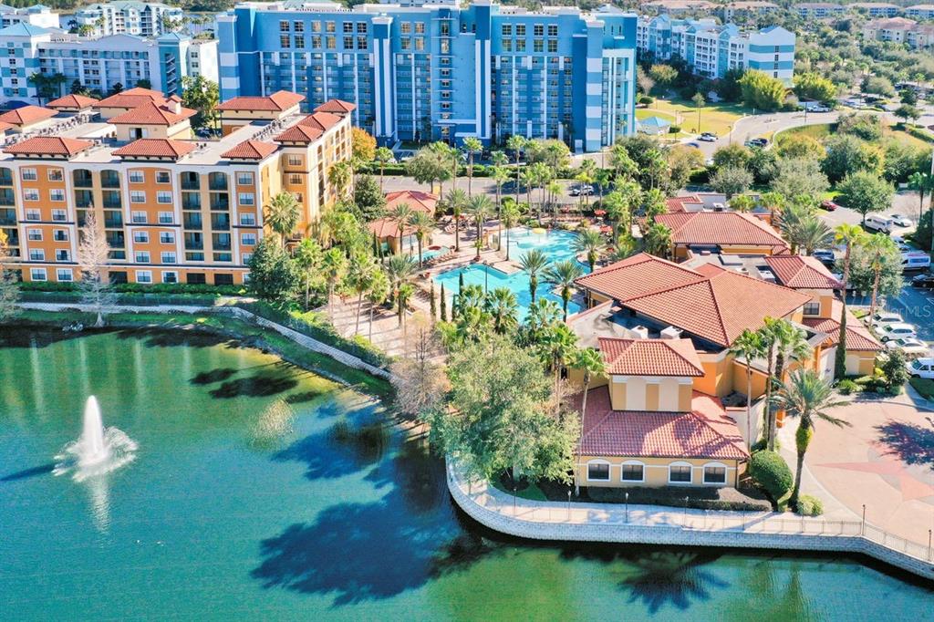 An aerial view of a resort complex featuring a lake, swimming pool, and multi-story buildings — 12556 FLORIDAYS RESORT DRIVE UNIT A-307, ORLANDO, FL